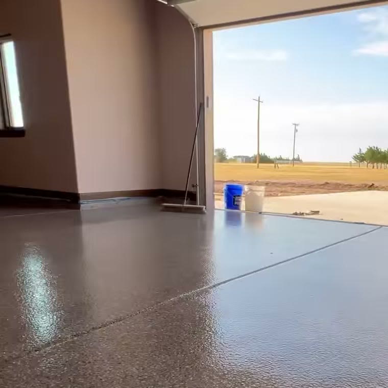 A glossy flake epoxy garage floor, the garage door open to a field.