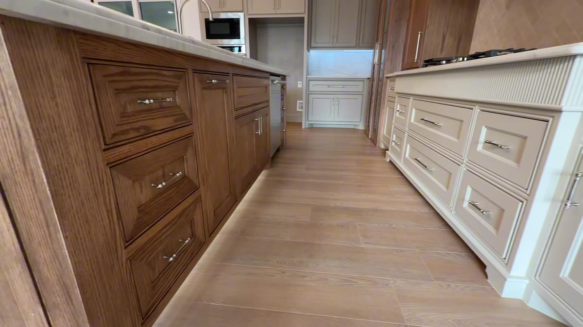 A long run of stained wood drawers and cabinets beside a white cabinet wall.