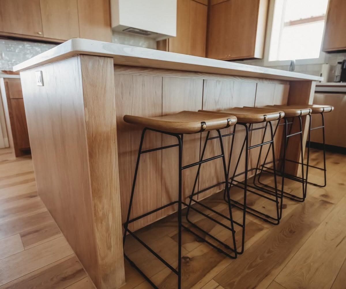 A pale wood kitchen island with four wood and metal bar stools.
