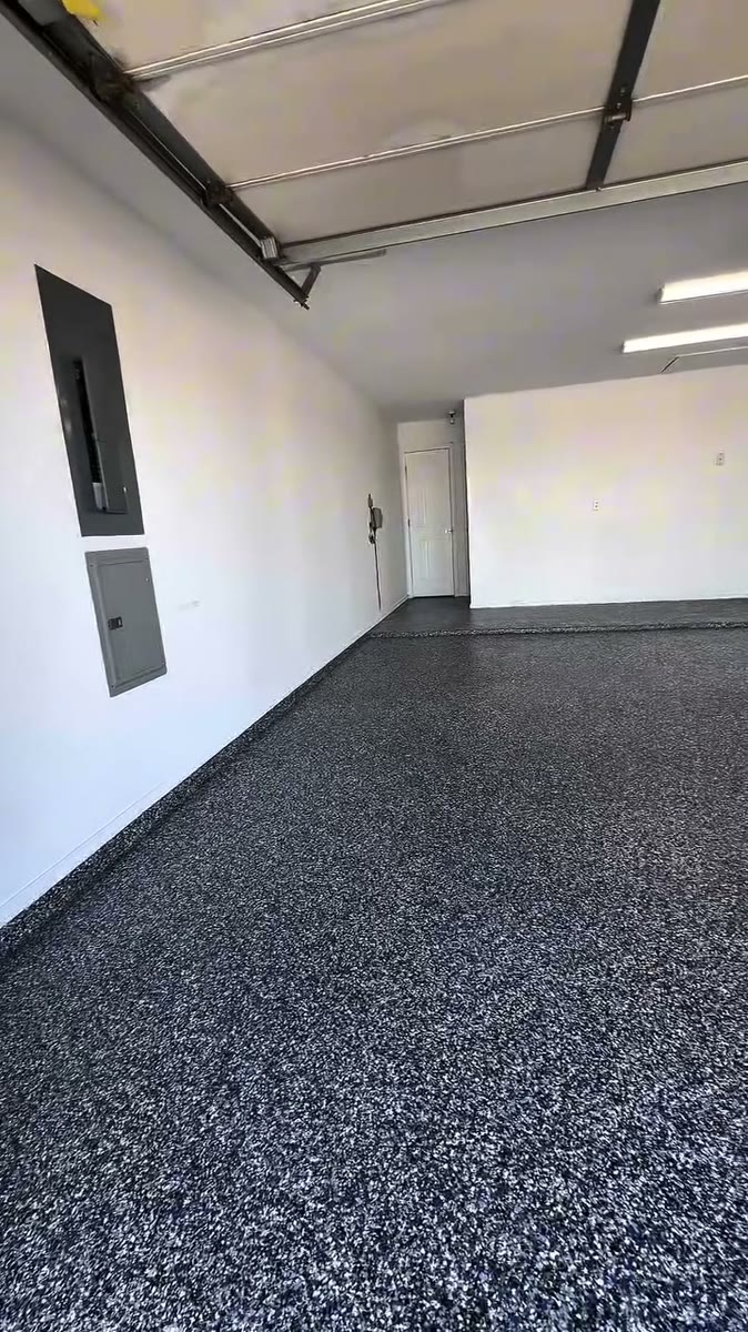 An empty two-car garage with a blue and grey flake epoxy floor.