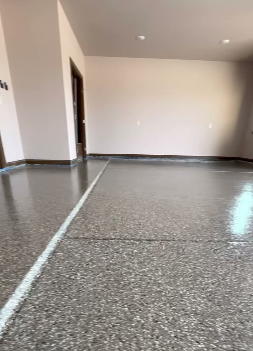A glossy flake epoxy garage floor, the garage door open to a field.