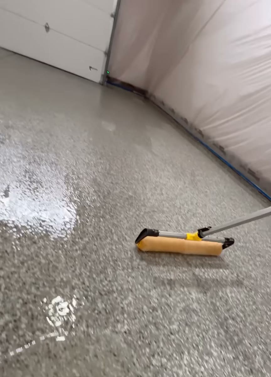 A fresh flake epoxy floor with a spiked roller lying on it.