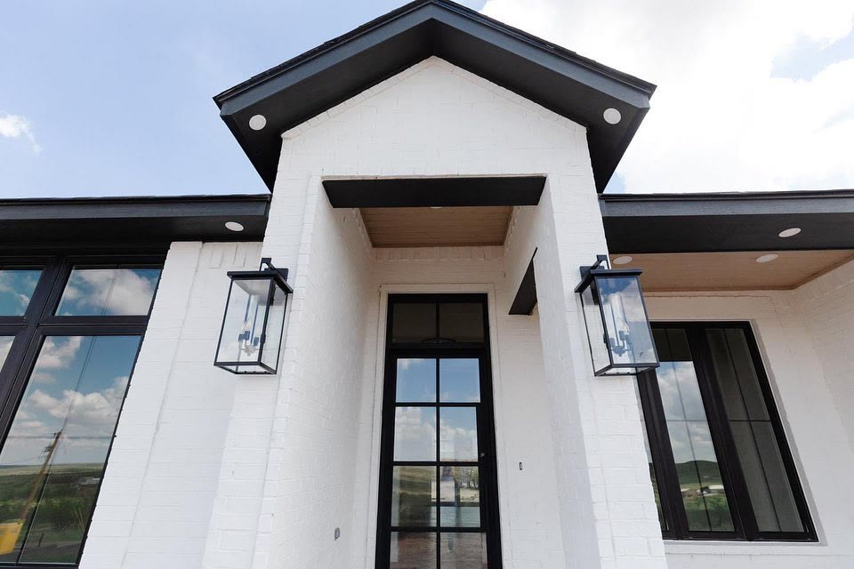 A white modern house with black window frames and black lantern lights.