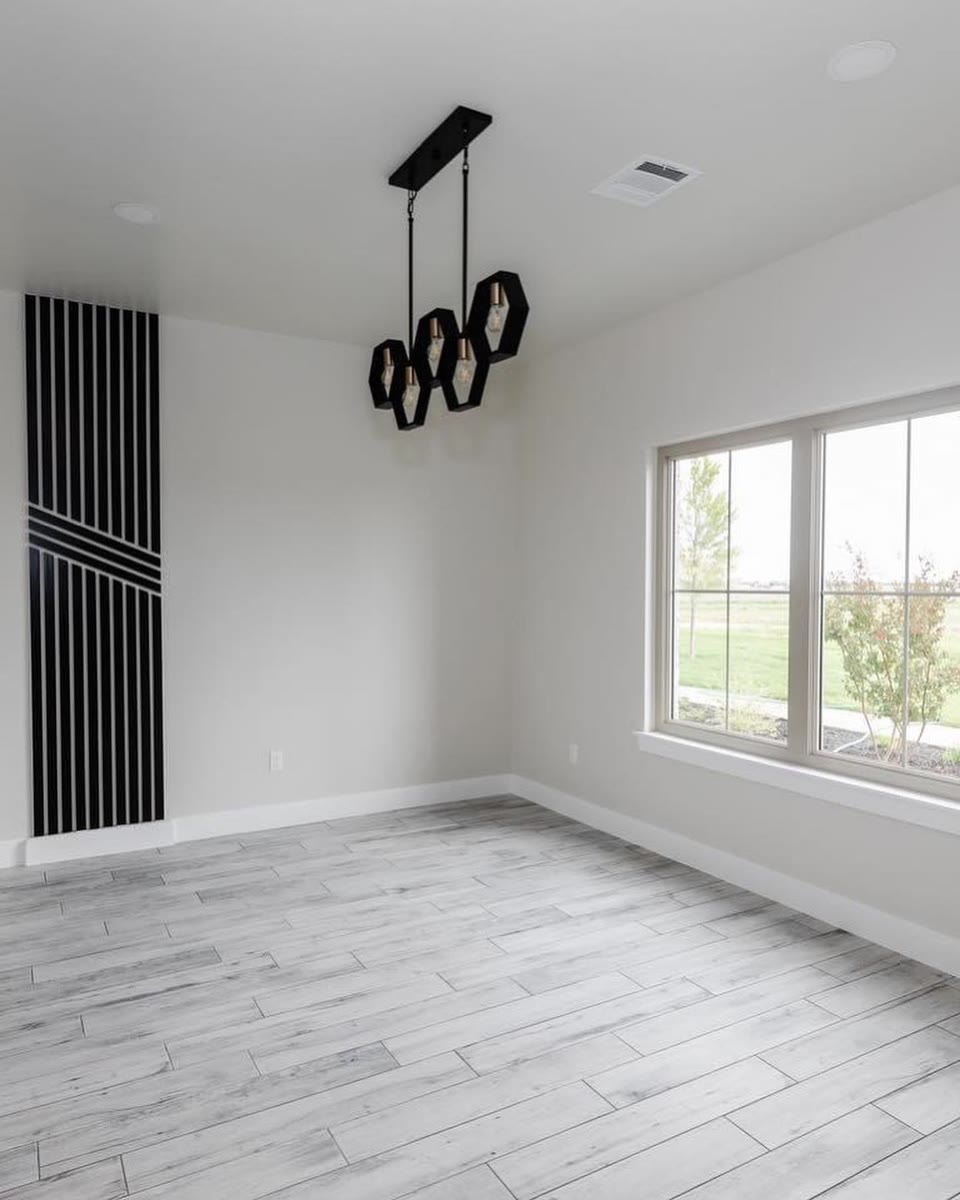 A white room with a black slatted feature wall and a black ring chandelier.