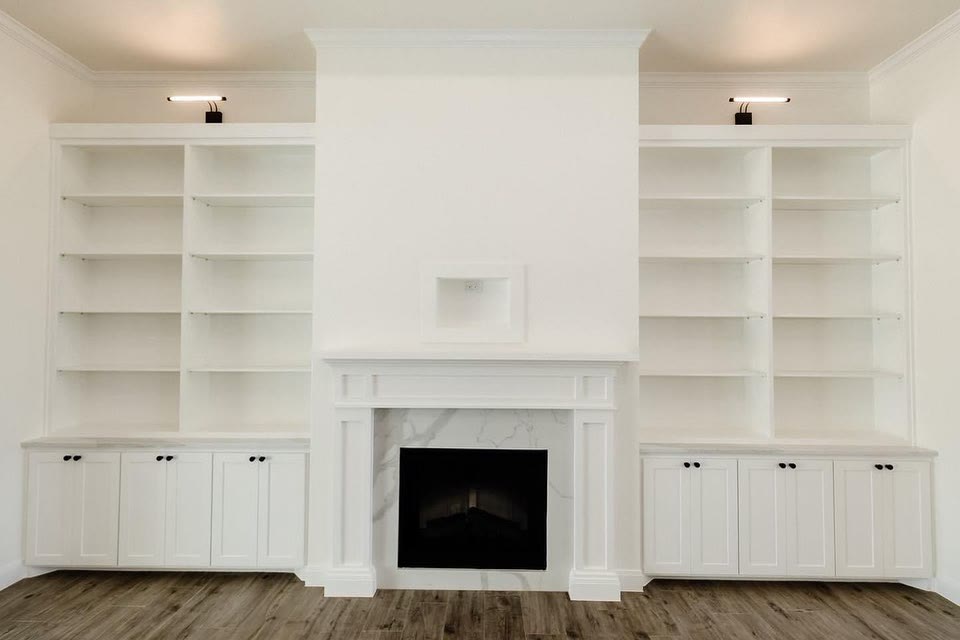 A white fireplace wall with open shelves and cabinets on both sides.