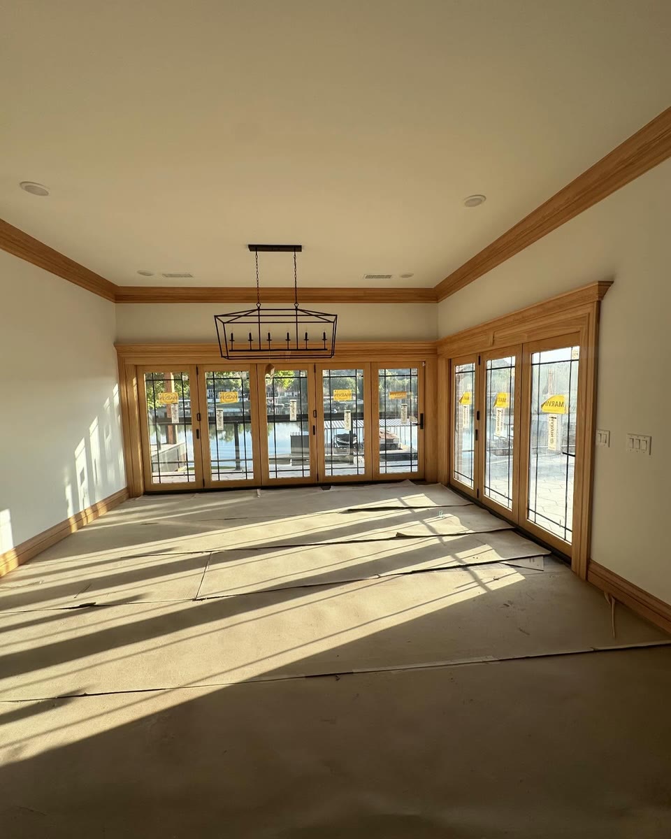 An empty room with stained wood trim around a wall of French doors and a lantern light.