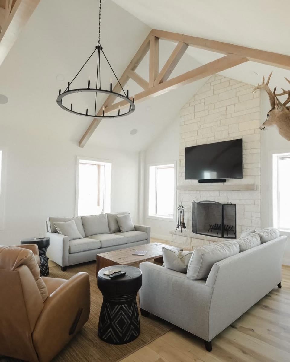 A living room under a vaulted ceiling with pale wood beams and a round chandelier.