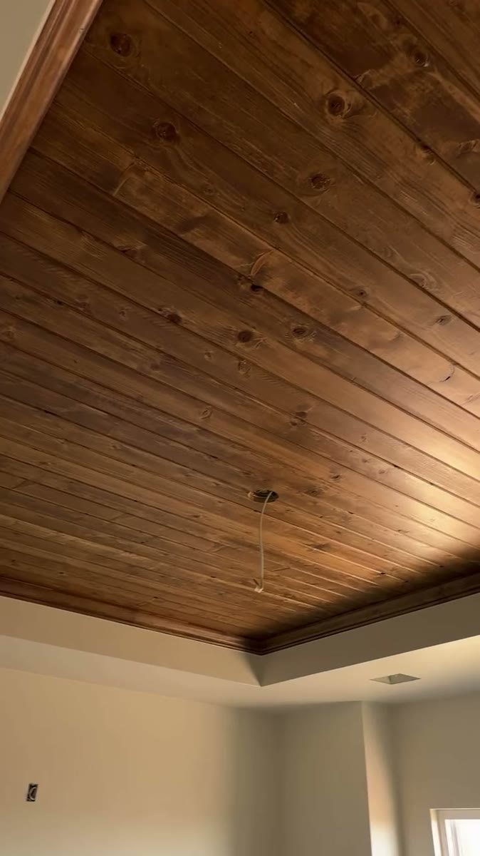 A bedroom tray ceiling finished in stained wood boards.