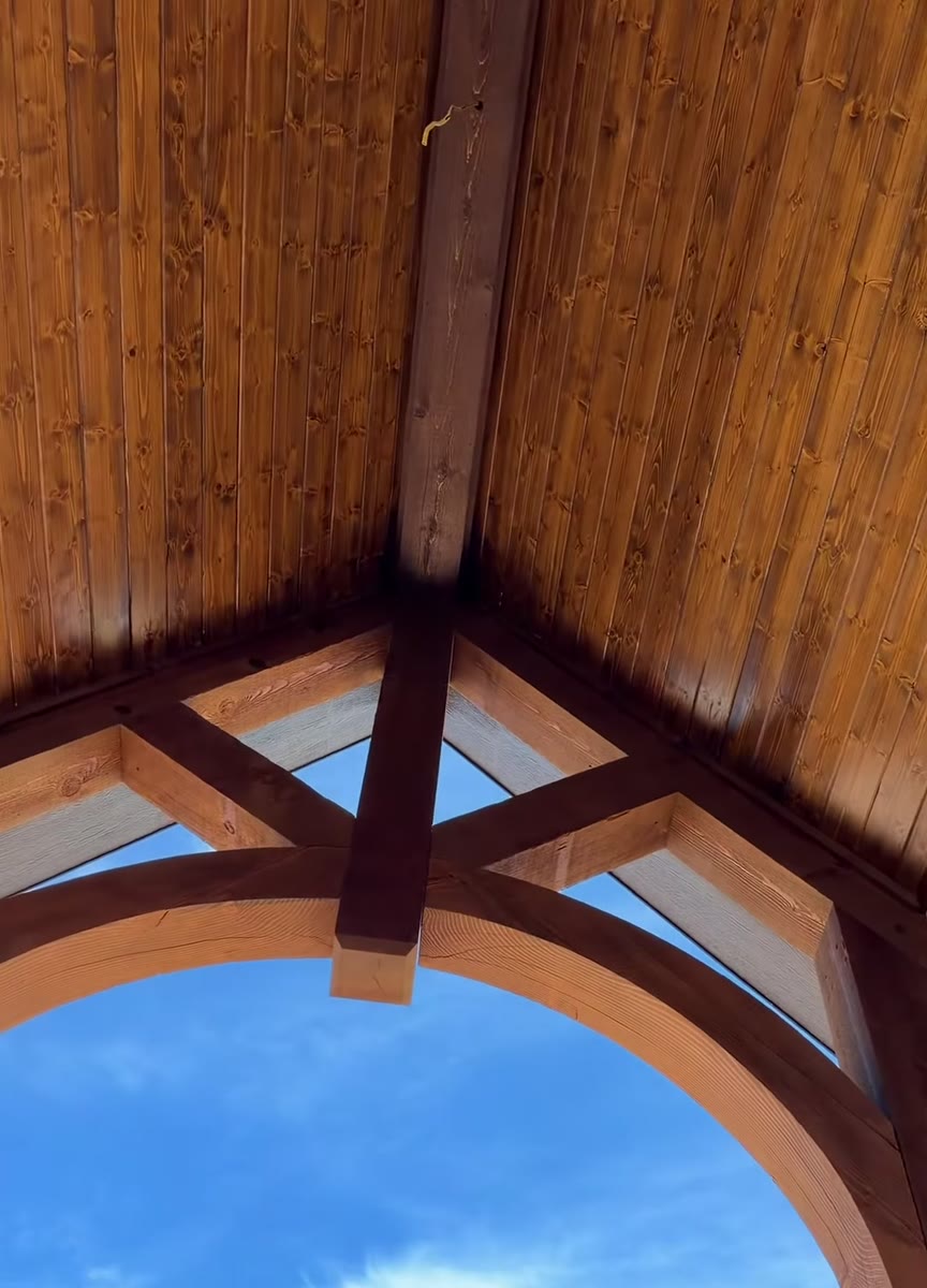 Stained timber trusses and an arched beam at the front of a porch.